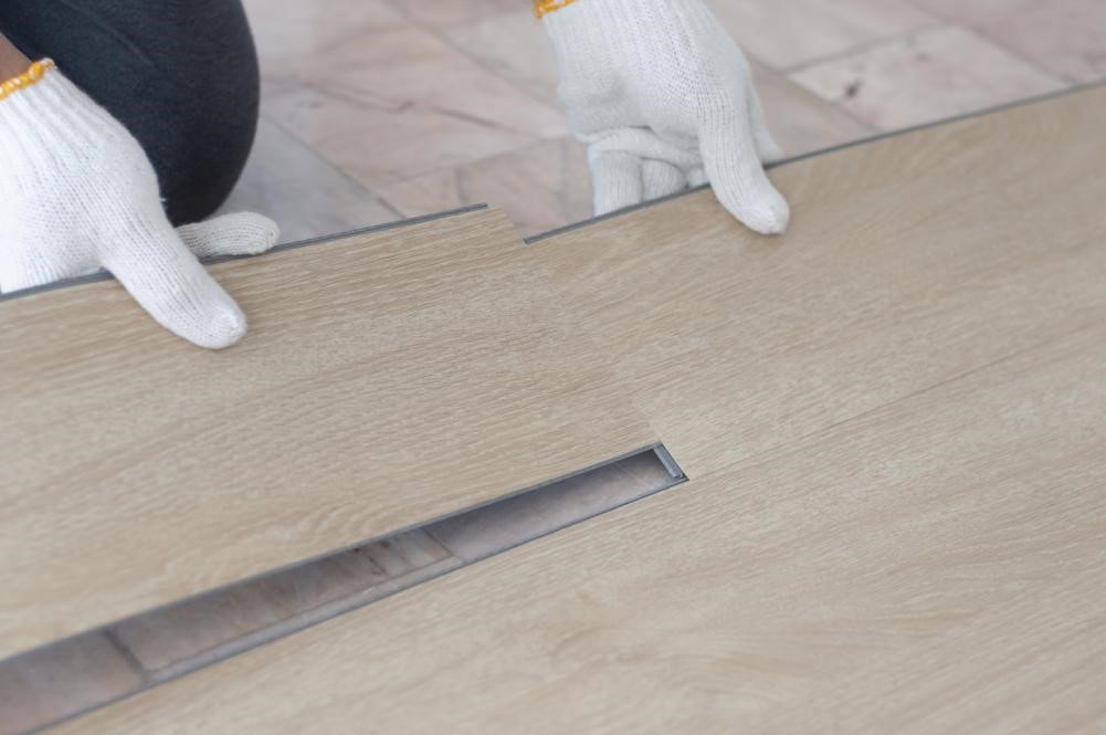 Why Are Luxury Vinyl Tiles So Popular? 2 A flooring specialist installing vinyl tiles that mimic the look of hardwood.